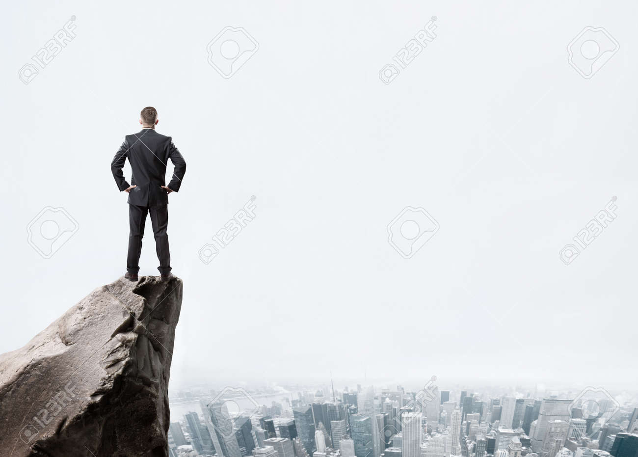Young businessman standing on edge of rock mountain and looking at the city - 41330275 Young businessman standing on edge of rock mountain and looking at the city - 41330275