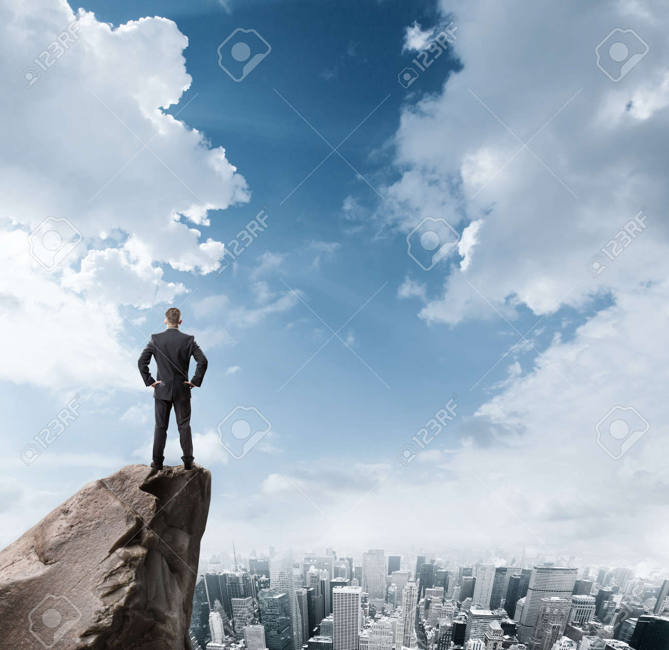 Young businessman standing on edge of rock mountain and looking at the city - 41330543 Young businessman standing on edge of rock mountain and looking at the city - 41330543