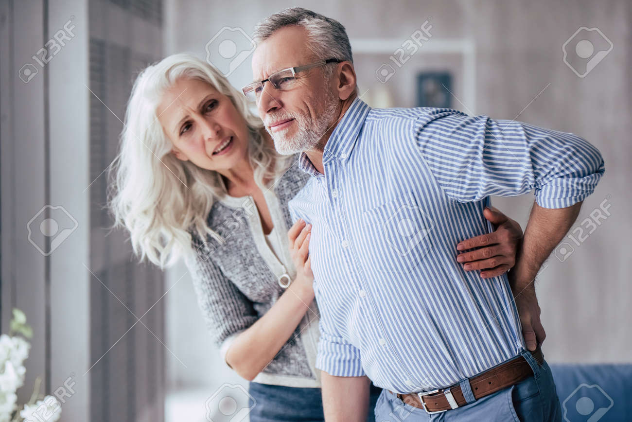 Senior Couple At Home Handsome Old Man Is Having Back Pain And His Attractive Old Woman Supports Him Stock Photo Picture And Royalty Free Image Image 98229467