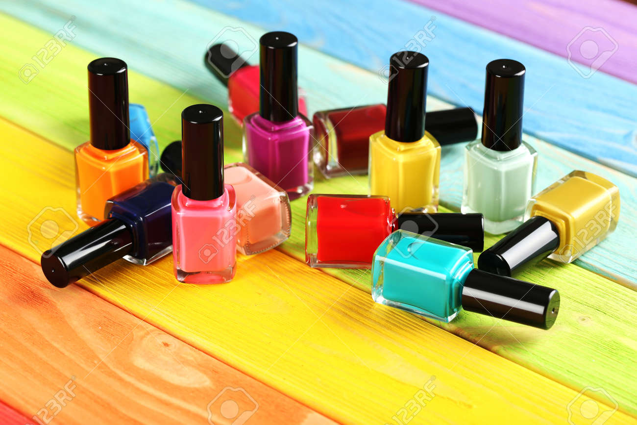 Bottles of nail polish on a colorful wooden table - 50299655 Bottles of nail polish on a colorful wooden table - 50299655