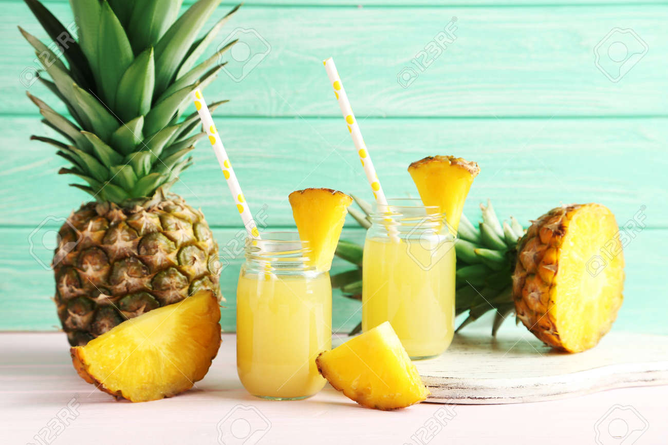 Bottles of pineapple juice on a pink wooden table - 51102030 Bottles of pineapple juice on a pink wooden table - 51102030