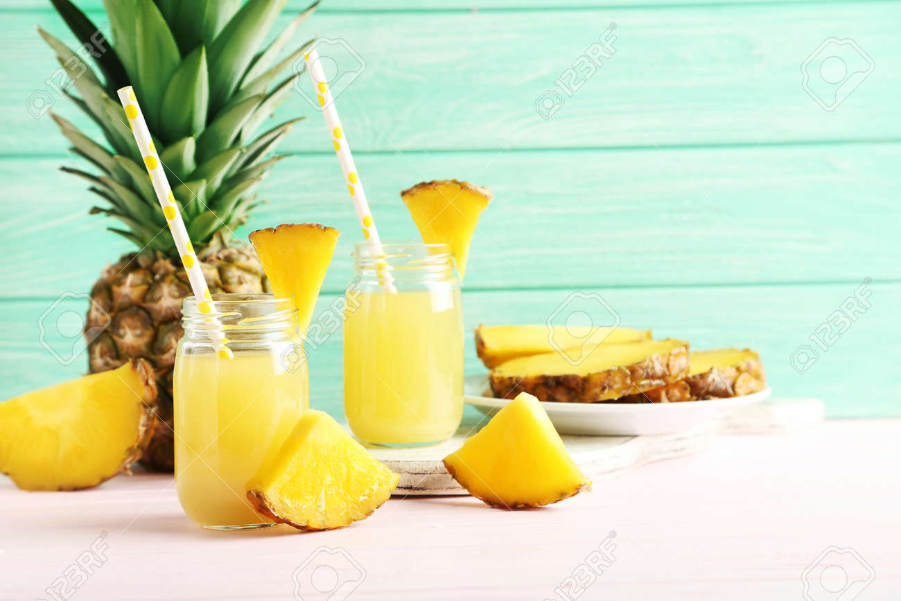 Bottles of pineapple juice on a pink wooden table - 51102031 Bottles of pineapple juice on a pink wooden table - 51102031