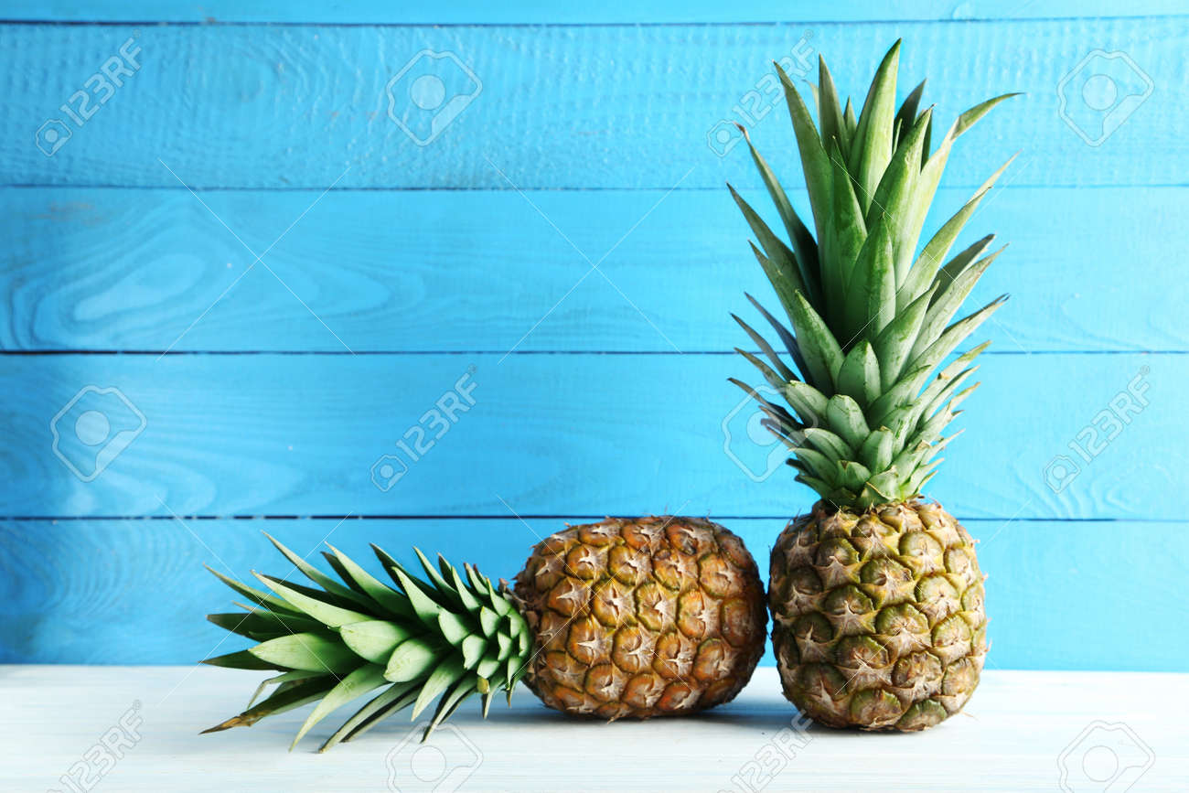 Ripe pineapples on a white wooden table - 55008567 Ripe pineapples on a white wooden table - 55008567