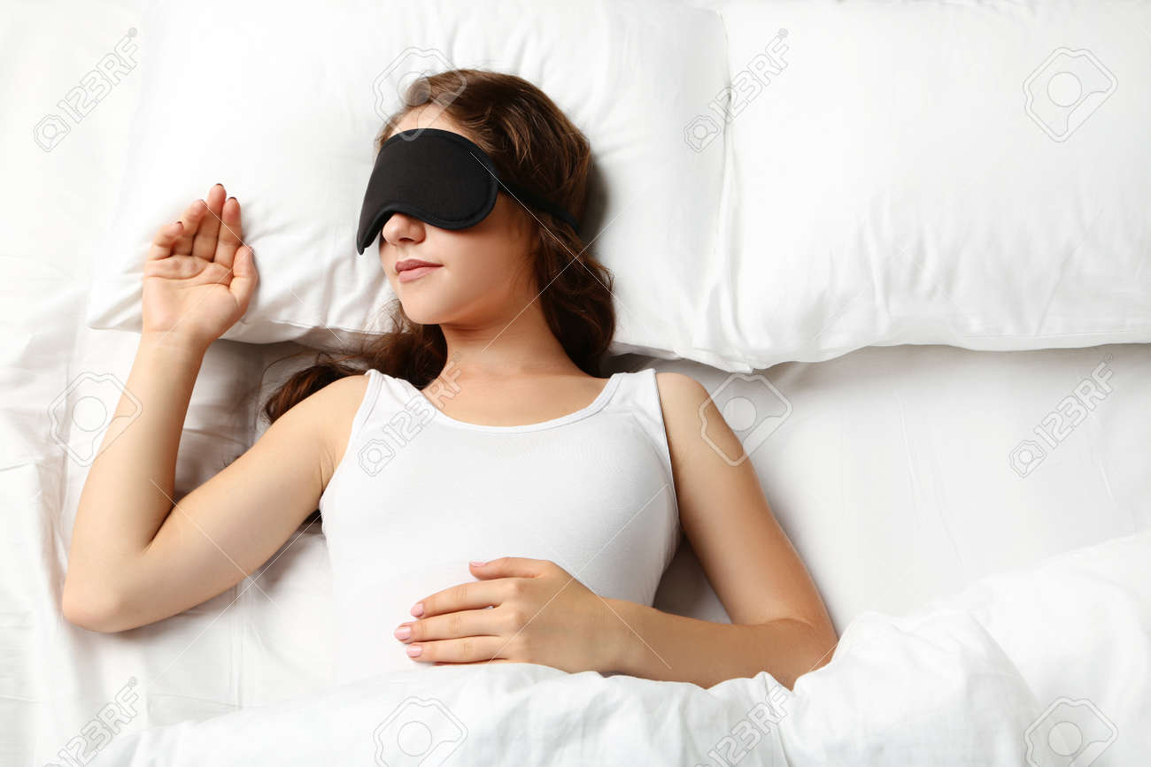 Young woman sleeping with eyemask in white bed - 83875800 Young woman sleeping with eyemask in white bed - 83875800