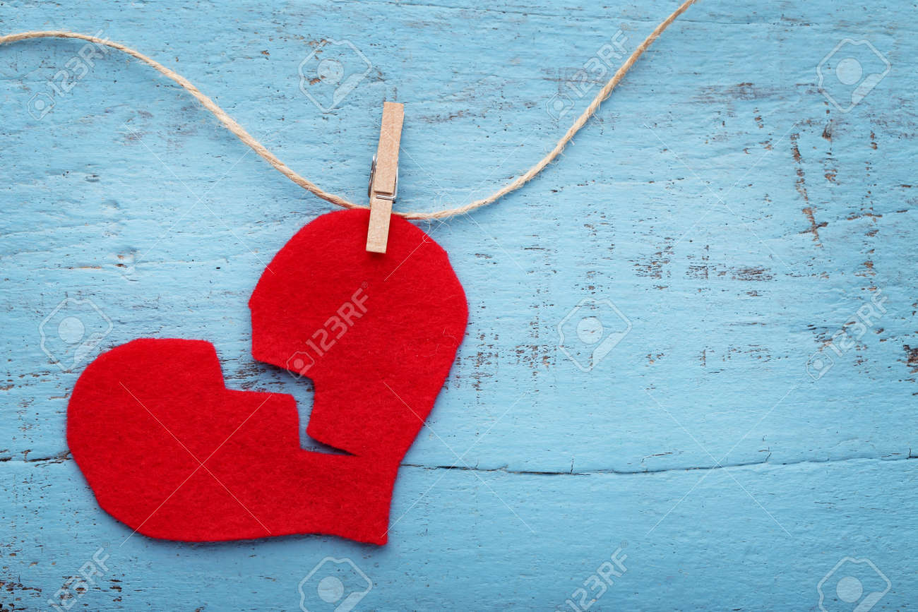 Broken red heart hanging on rope on blue wooden table - 92282614 Broken red heart hanging on rope on blue wooden table - 92282614