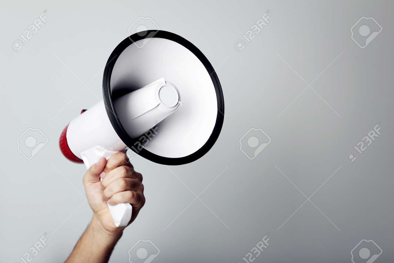 Female hand holding megaphone on grey background - 96380364 Female hand holding megaphone on grey background - 96380364