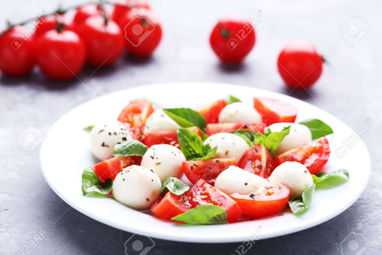 Mozzarella, tomatoes and basil leafs in plate on wooden table - 110047572 Mozzarella, tomatoes and basil leafs in plate on wooden table - 110047572