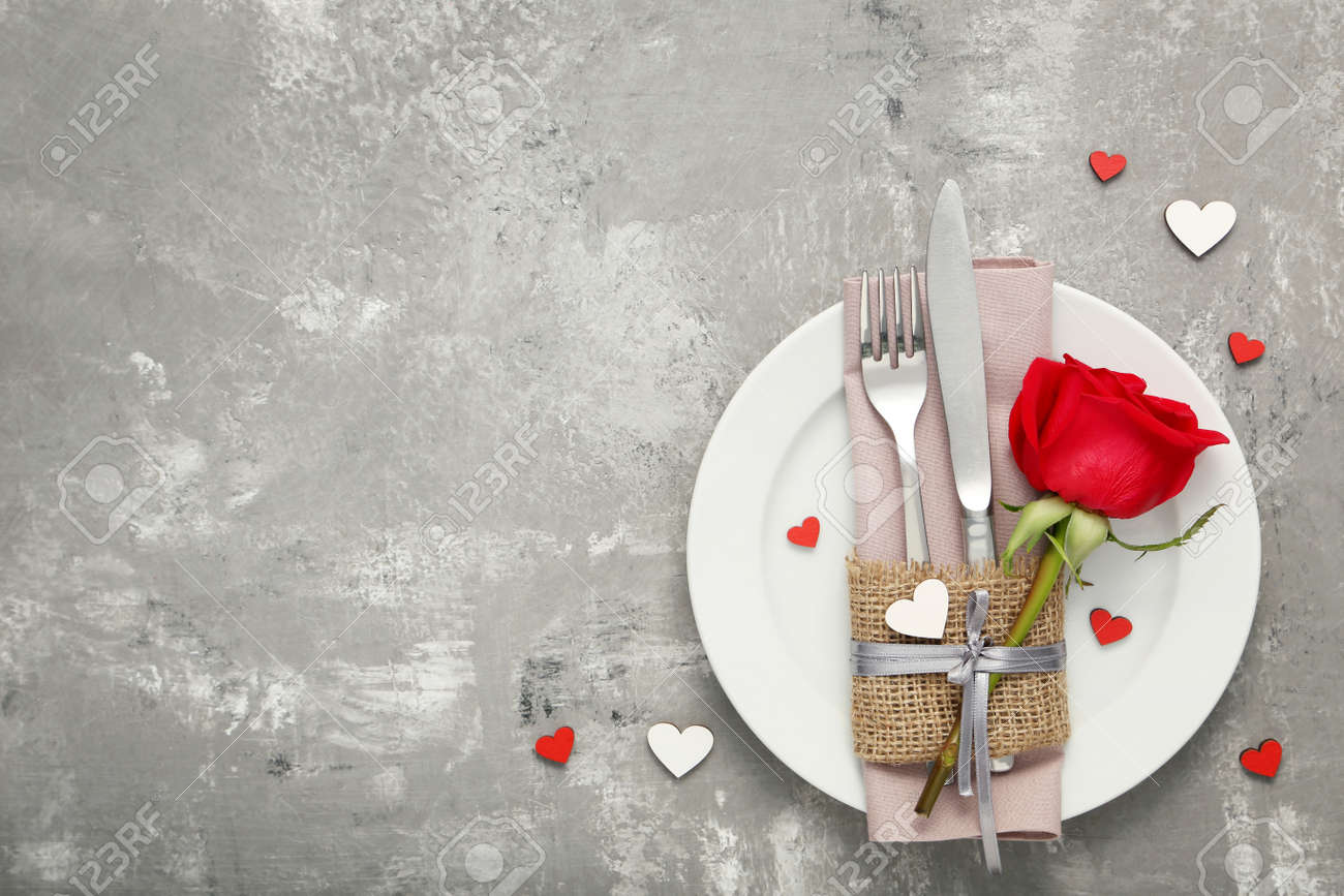 Kitchen cutlery with red rose in white plate on wooden table - 115383997 Kitchen cutlery with red rose in white plate on wooden table - 115383997