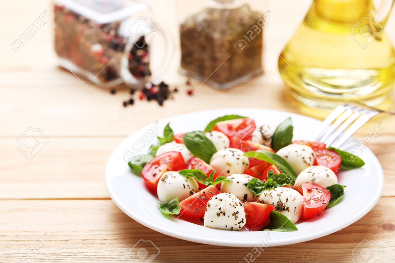 Mozzarella, tomatoes and basil leafs on brown wooden table - 116599513 Mozzarella, tomatoes and basil leafs on brown wooden table - 116599513