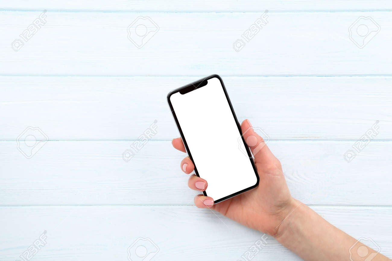 Smartphone in female hand on wooden background - 127094216 Smartphone in female hand on wooden background - 127094216
