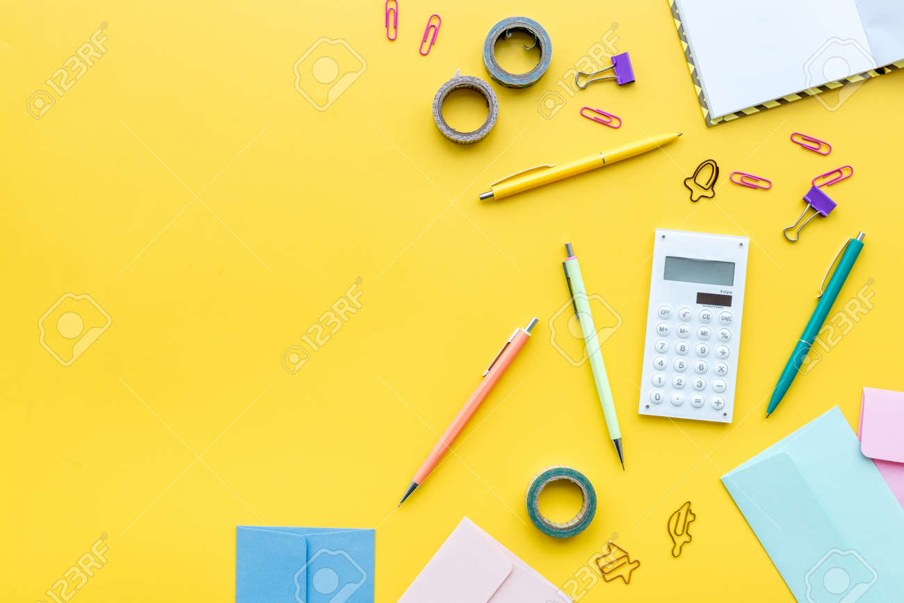 scattered stationery on students desk yellow background top student desk top