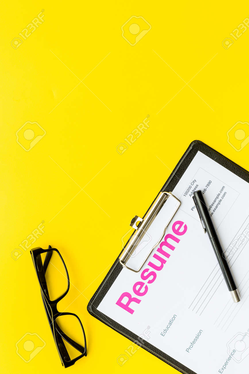resume Pad Resume looking for work concept resume on pad near pen and glasses stock yellow background top