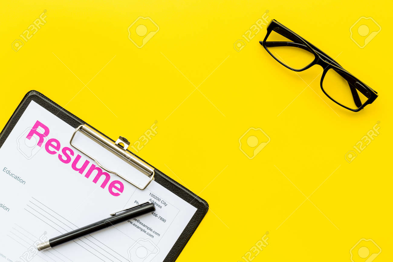 resume Pad Resume looking for work concept resume on pad near pen and glasses stock yellow background top