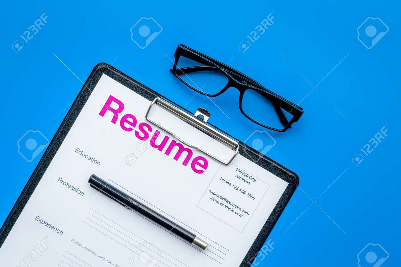 resume Pad Resume looking for work concept resume on pad near pen and glasses stock blue background top