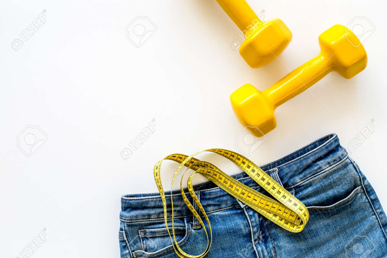 weight loss concept with jeans bars and measuring tape on white measure for weight loss