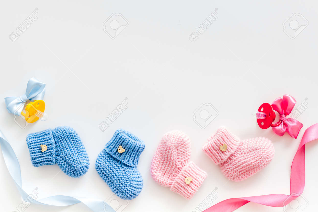 Blue and pink knitted footwear with dummy for baby boy and girl on white background top view mock up - 129481038 Blue and pink knitted footwear with dummy for baby boy and girl on white background top view mock up - 129481038
