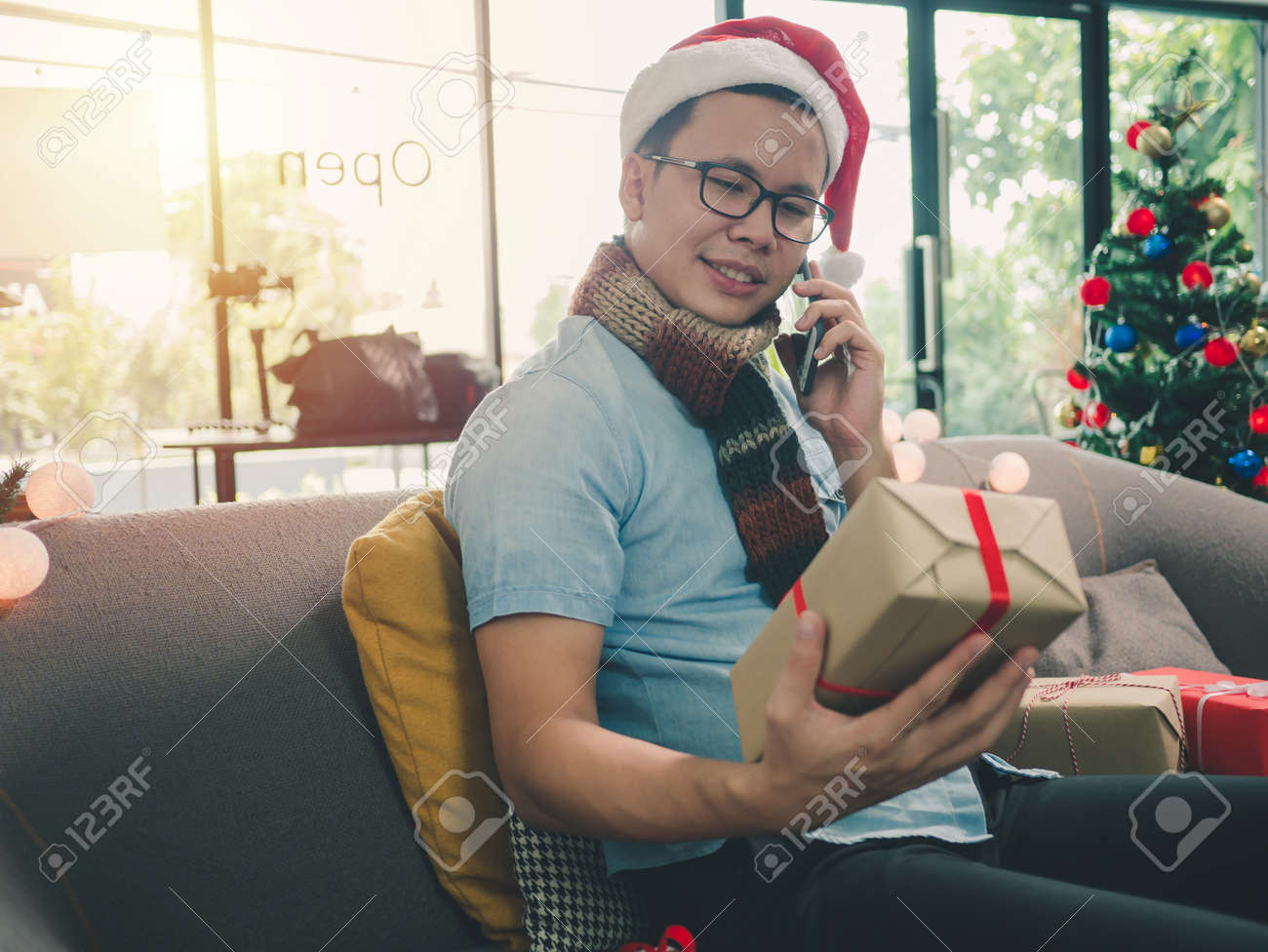 クリスマスプレゼントボックスを持つアジアの男の手 カフェ喫茶店でスマホを使う アジアの男性は クリスマス休暇のためにプレゼントを準備しています の写真素材 画像素材 Image