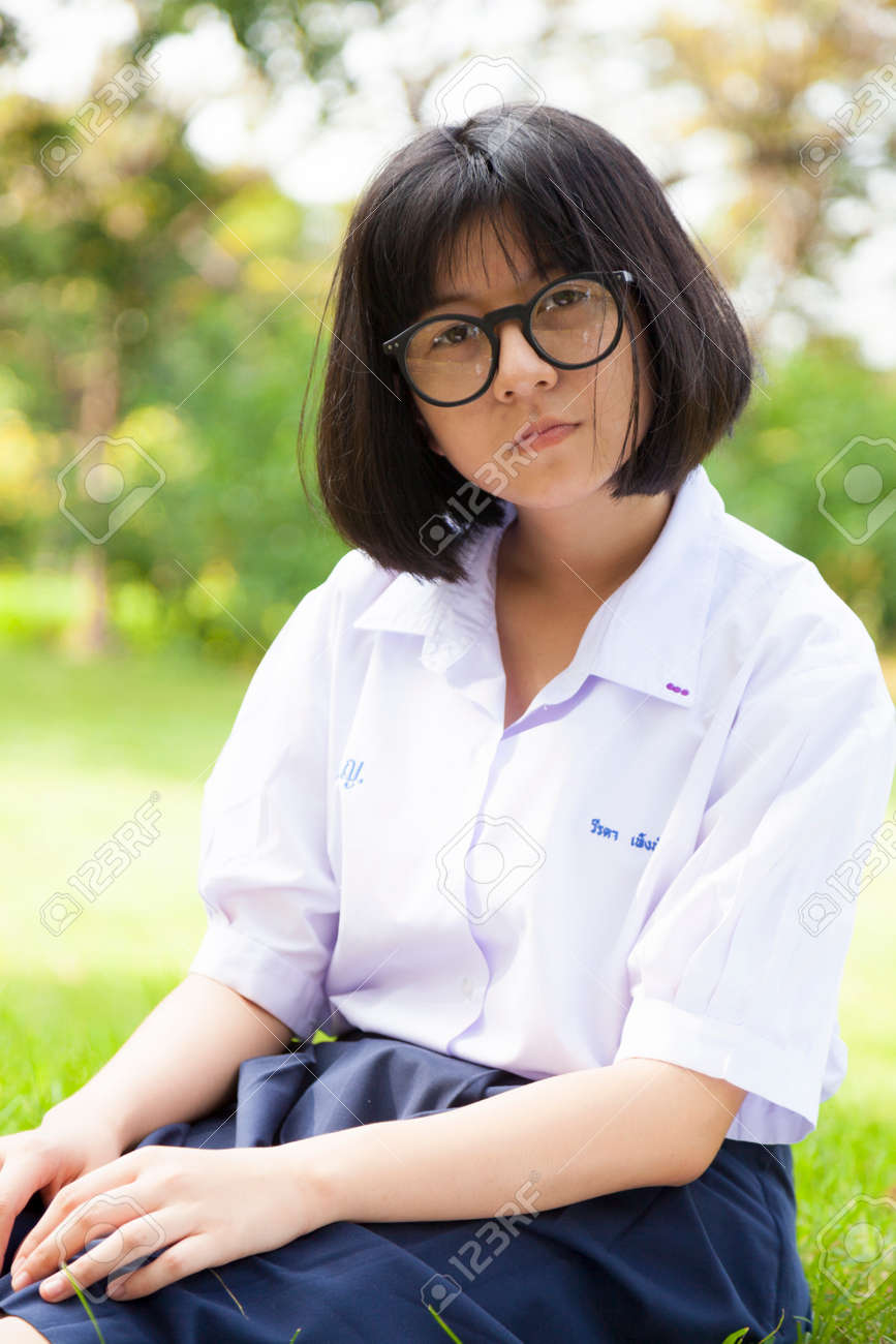 女子高生では 芝生の上に座っているメガネの女の子と思われます 懐疑的なスタンスは します の写真素材 画像素材 Image