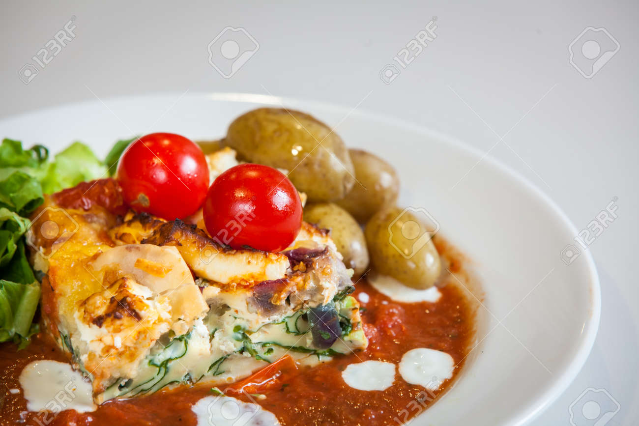 フェタチーズとほうれん草の層状キッシュ トマトソース チェリー トマト ロースト ポテト添え の写真素材 画像素材 Image