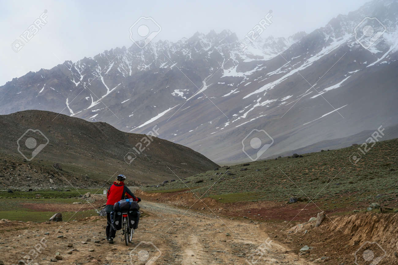 パキスタン北部シャンドゥール峠に向けて困難な山道の上り坂に彼女の自転車を押す女性 の写真素材 画像素材 Image