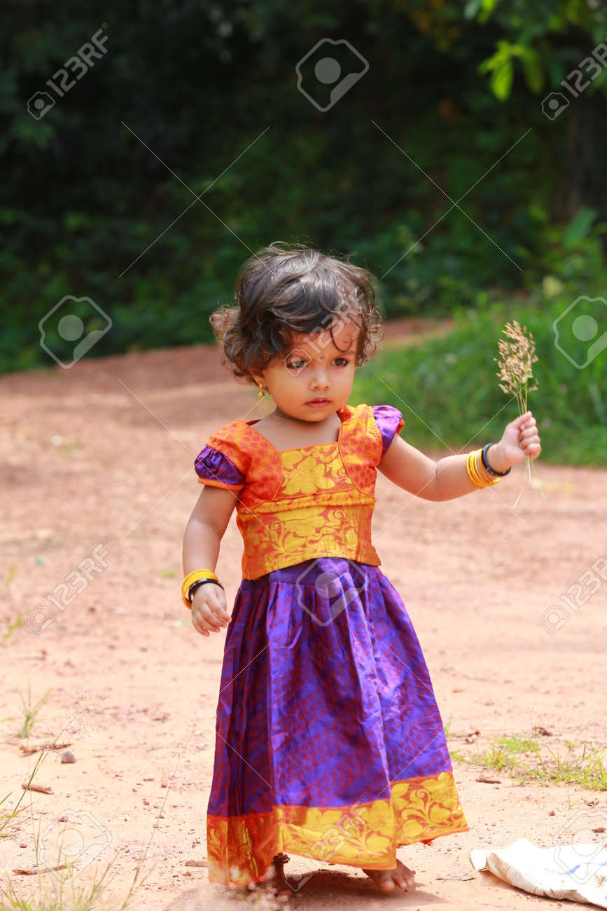 Niñas Del Sur De La India Con Faldas Largas Y Blusas Tradicionales, Arrancando Las Flores De La Hierba De Pelo Ondulado, Fondo Verde. Fotos, Imágenes Y Fotografía De Archivo Libres