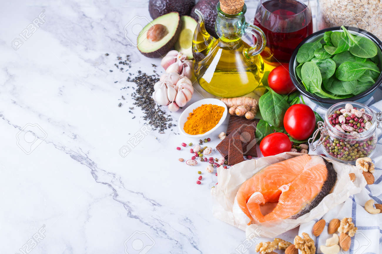 Balanced diet food concept. Assortment of healthy food low cholesterol, spinach avocado red wine green tea salmon tomato flax chia seeds turmeric garlic nuts olive oil - 163638007 Balanced diet food concept. Assortment of healthy food low cholesterol, spinach avocado red wine green tea salmon tomato flax chia seeds turmeric garlic nuts olive oil - 163638007