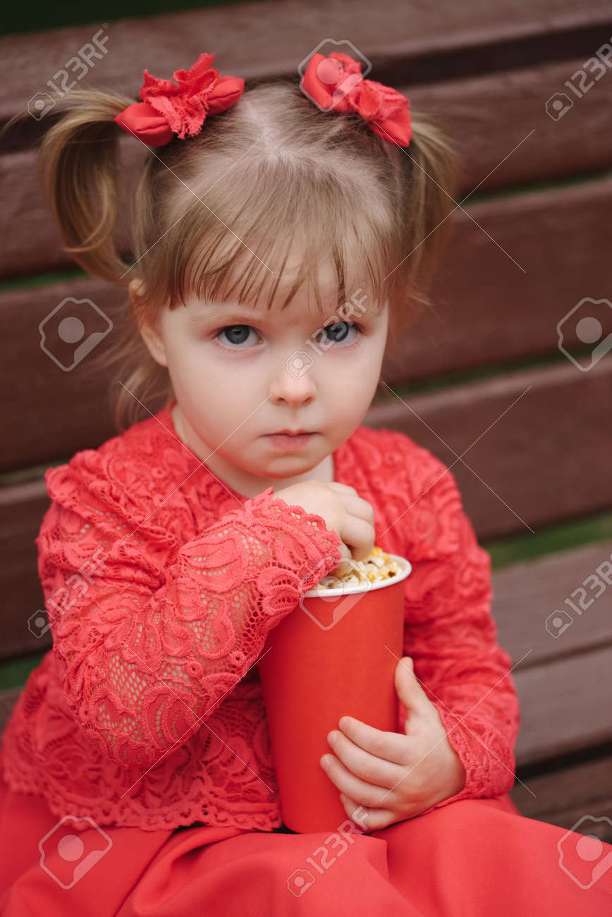 little girl with cup of popcorn in park stock photo picture and
