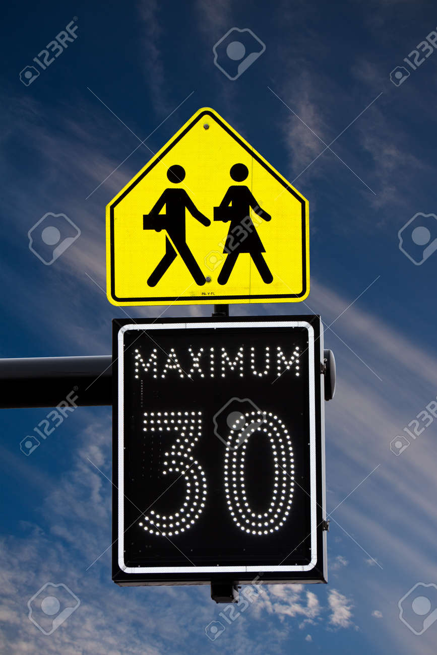 白い雲と青空スクール ゾーンの始まりを示す人看板の下での電気の 30 キロ速度制限標識 の写真素材 画像素材 Image