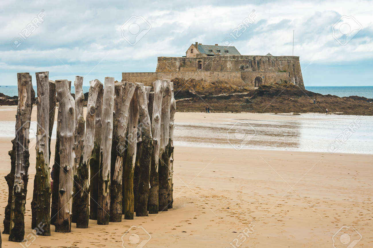 干潮時の海岸の木製ポールとフォートナショナル フランス ブルターニュ ブルターニュのサン マロ島の17世紀の要塞 の写真素材 画像素材 Image