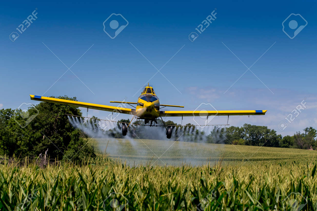 A crop duster applies chemicals to a field of vegetation. - 44030322 A crop duster applies chemicals to a field of vegetation. - 44030322