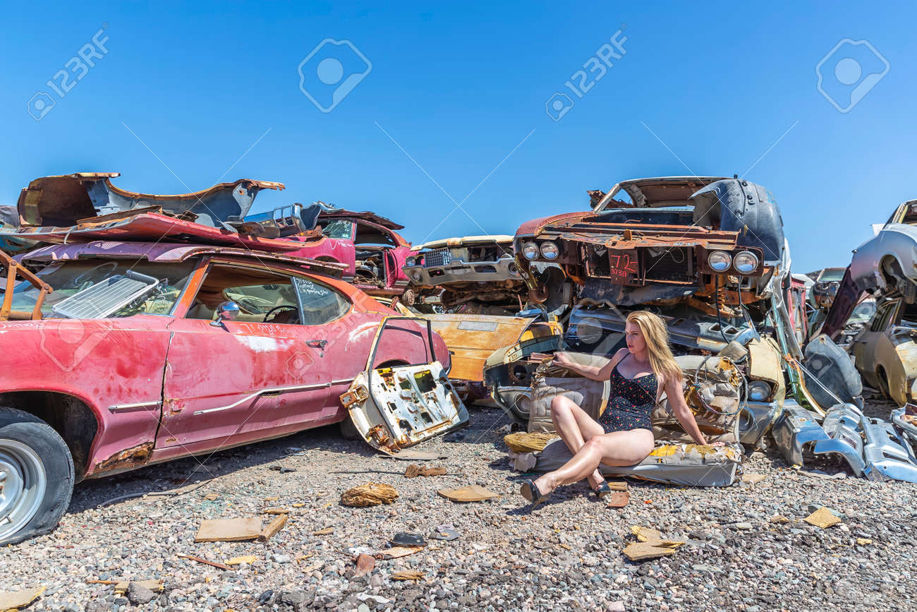 A beautiful blonde bikini model posing in a auto salvage yard. Stock Photo - 101164809