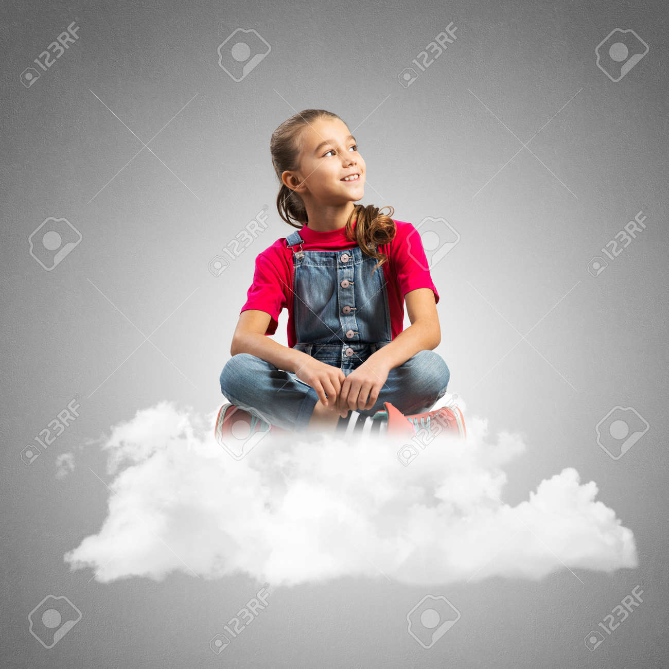 コンクリートの壁の背景に対して雲の上に座ってかわいい子供の女の子 の写真素材 画像素材 Image