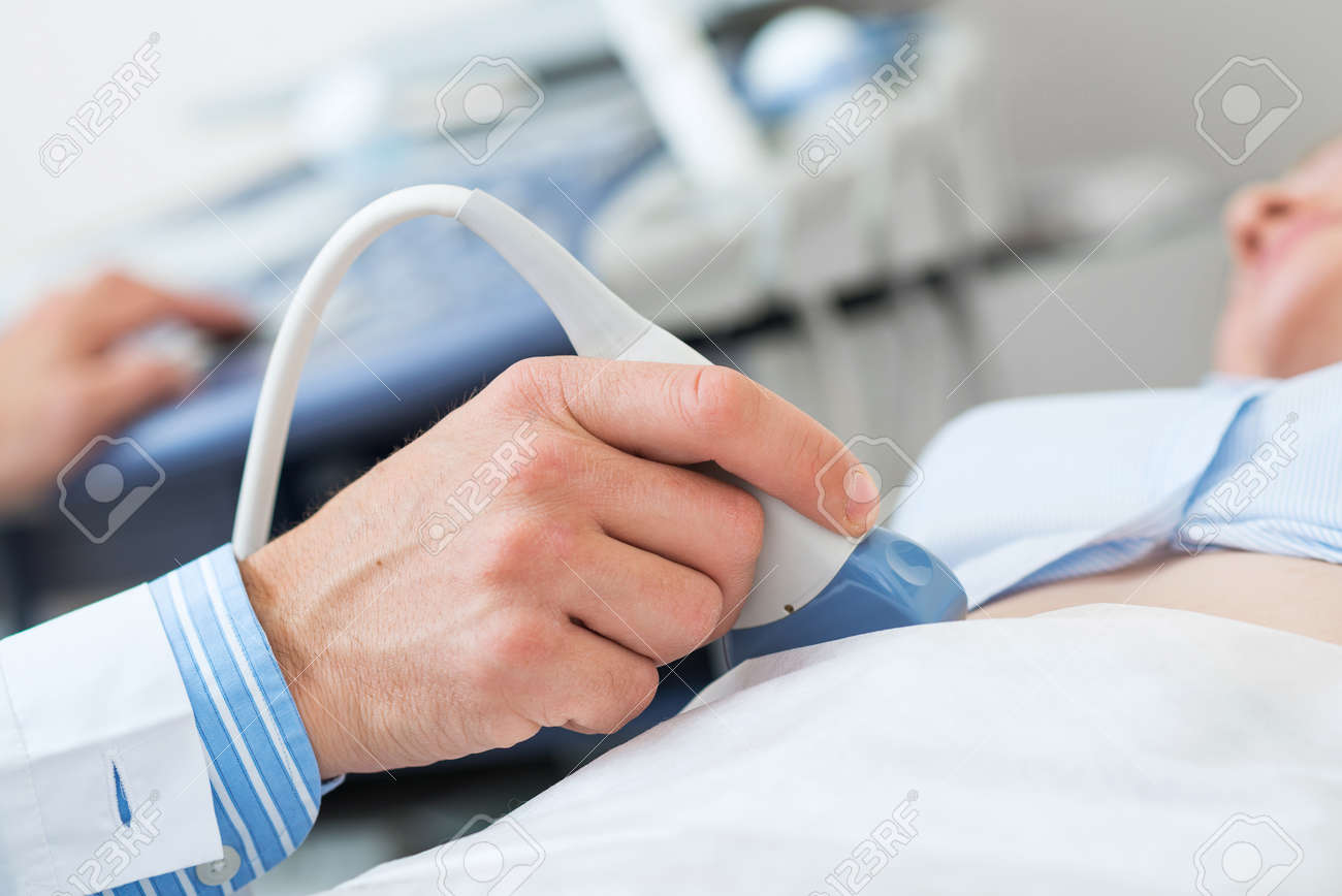 Sonogram procedure at modern hospital. Close-up doctors hand moving transducer on human belly. Professional clinical diagnostics and treatment. Ultrasound examination of human body internal organs - 132432640 Sonogram procedure at modern hospital. Close-up doctors hand moving transducer on human belly. Professional clinical diagnostics and treatment. Ultrasound examination of human body internal organs - 132432640