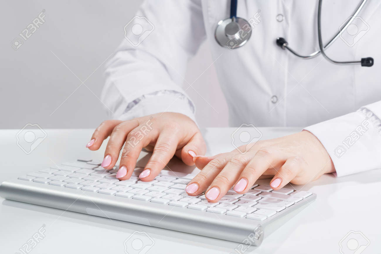 Close up doctor typing on computer keyboard. Female physician in white coat with stethoscope sitting at desk. Professional medical diagnosis and treatment in clinic. Healthcare and medicine. - 148682399 Close up doctor typing on computer keyboard. Female physician in white coat with stethoscope sitting at desk. Professional medical diagnosis and treatment in clinic. Healthcare and medicine. - 148682399