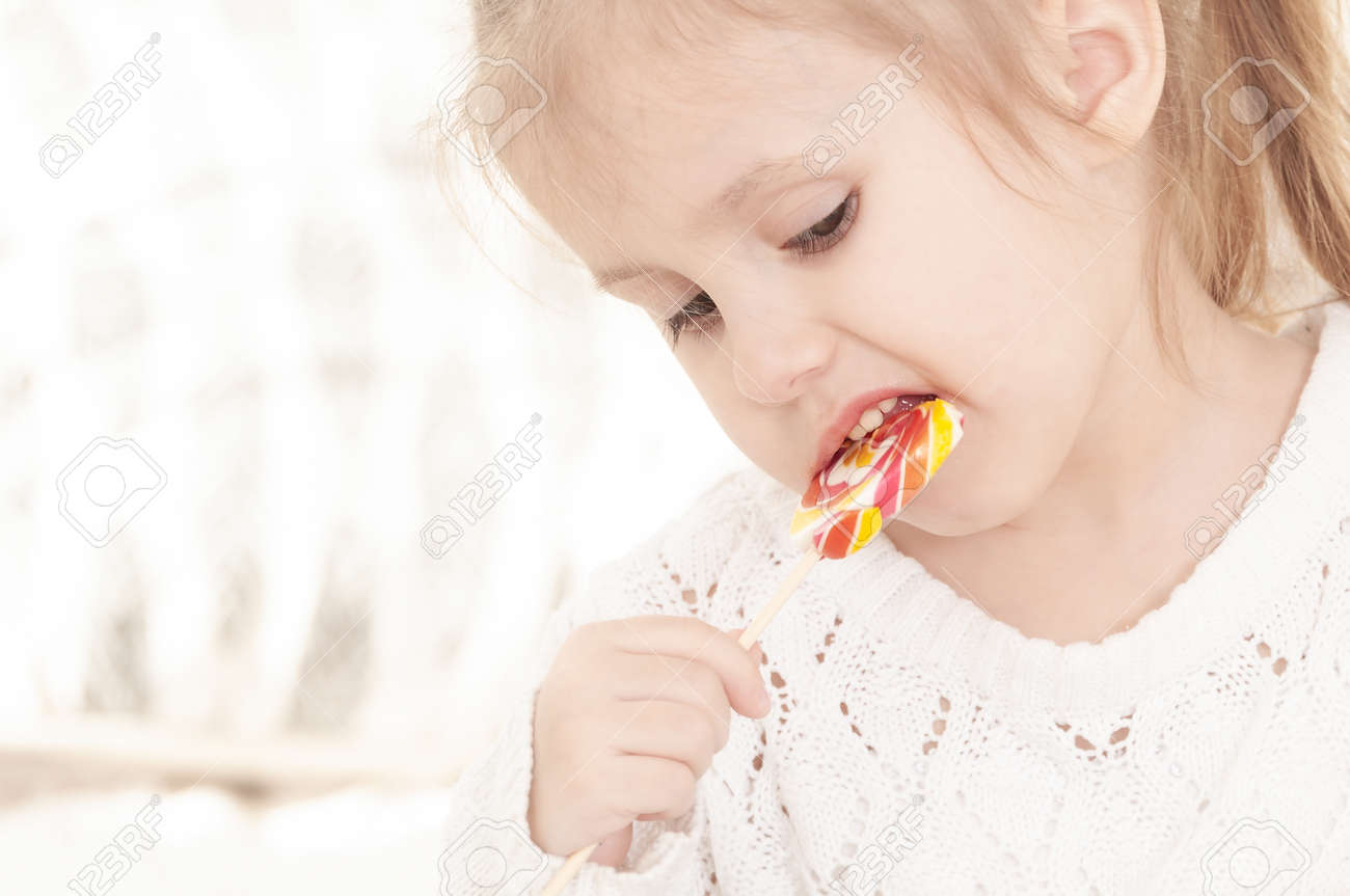 portrait of a three year old smiling little girl eating a candy - 144670639 portrait of a three year old smiling little girl eating a candy - 144670639