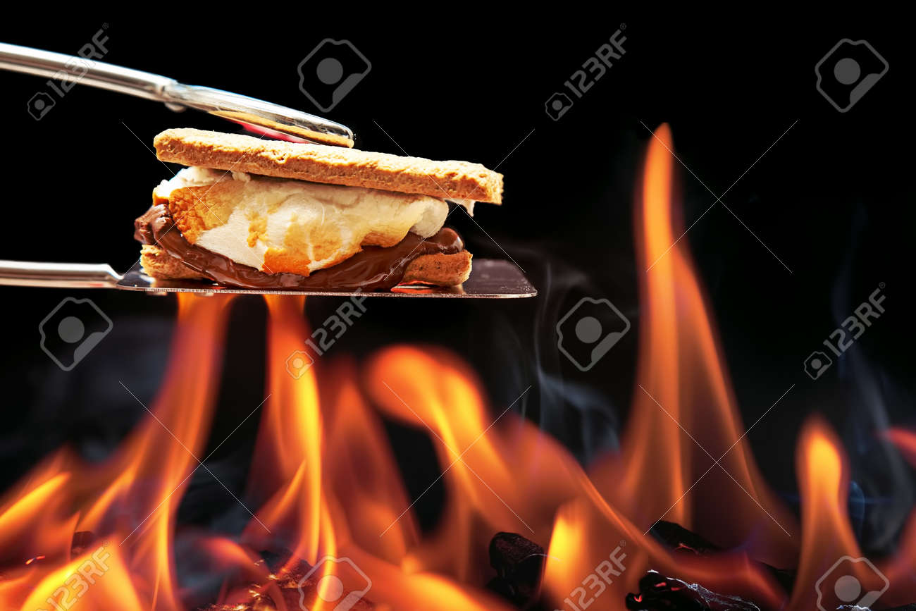 Smore cooking over fire with melting marshmallow and chocolate oozing out of graham crackers. - 59099390 Smore cooking over fire with melting marshmallow and chocolate oozing out of graham crackers. - 59099390