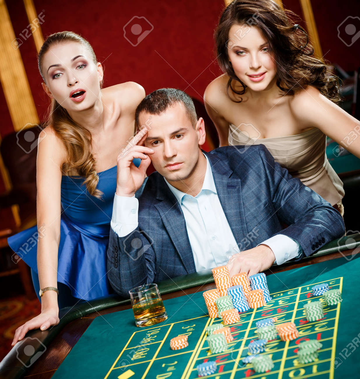 Man With Two Girls Playing Roulette At The Casino. Addiction To ...