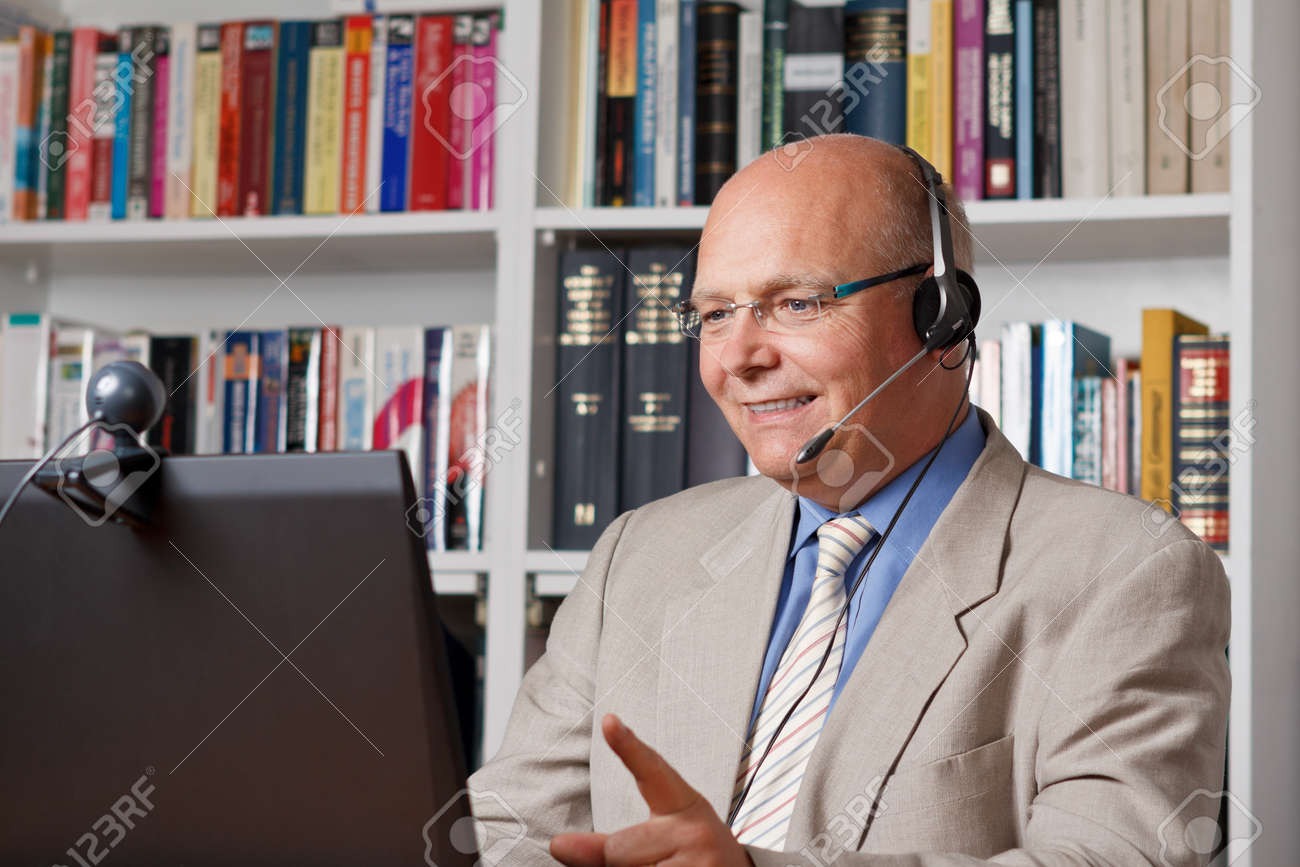 Laughing senior empoyee telephoning by means of computer, webcam und headset - 25745329 Laughing senior empoyee telephoning by means of computer, webcam und headset - 25745329