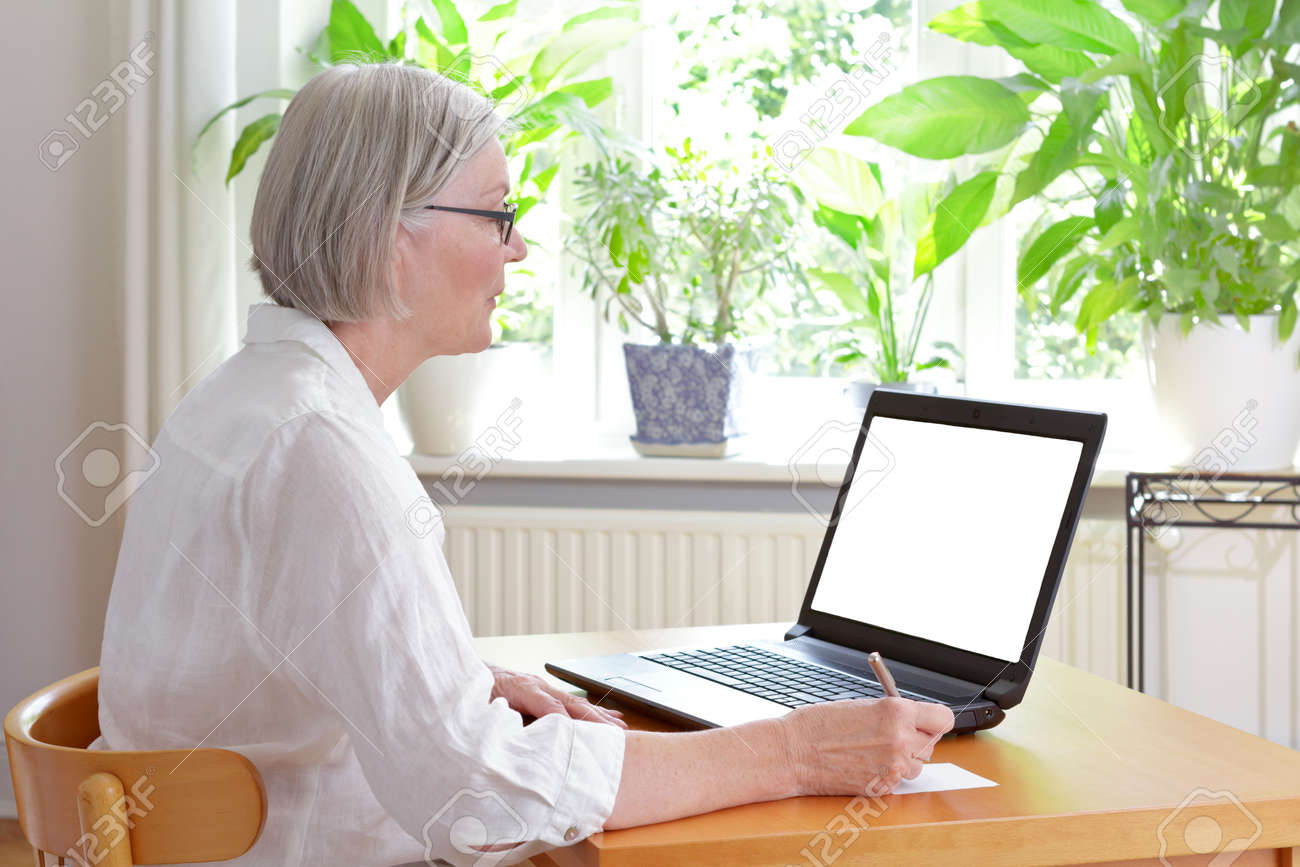 Senior woman at home in front of her laptop taking notes, online advice or e-learning concept template, white screen, copy space - 81728545 Senior woman at home in front of her laptop taking notes, online advice or e-learning concept template, white screen, copy space - 81728545