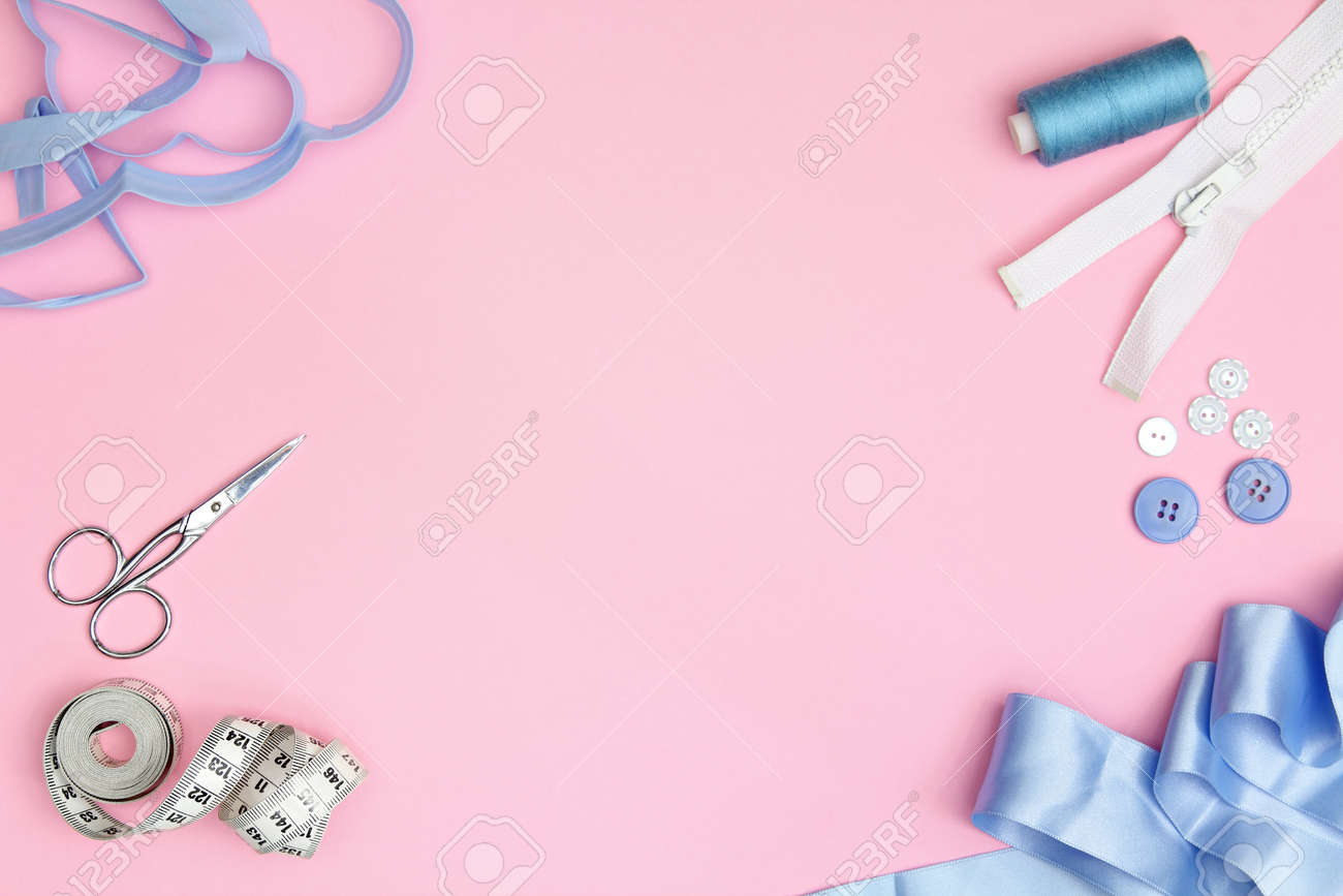Sewing accessories on a pink background with needles, spool of thread, scissors and a tape measure - 165236948 Sewing accessories on a pink background with needles, spool of thread, scissors and a tape measure - 165236948