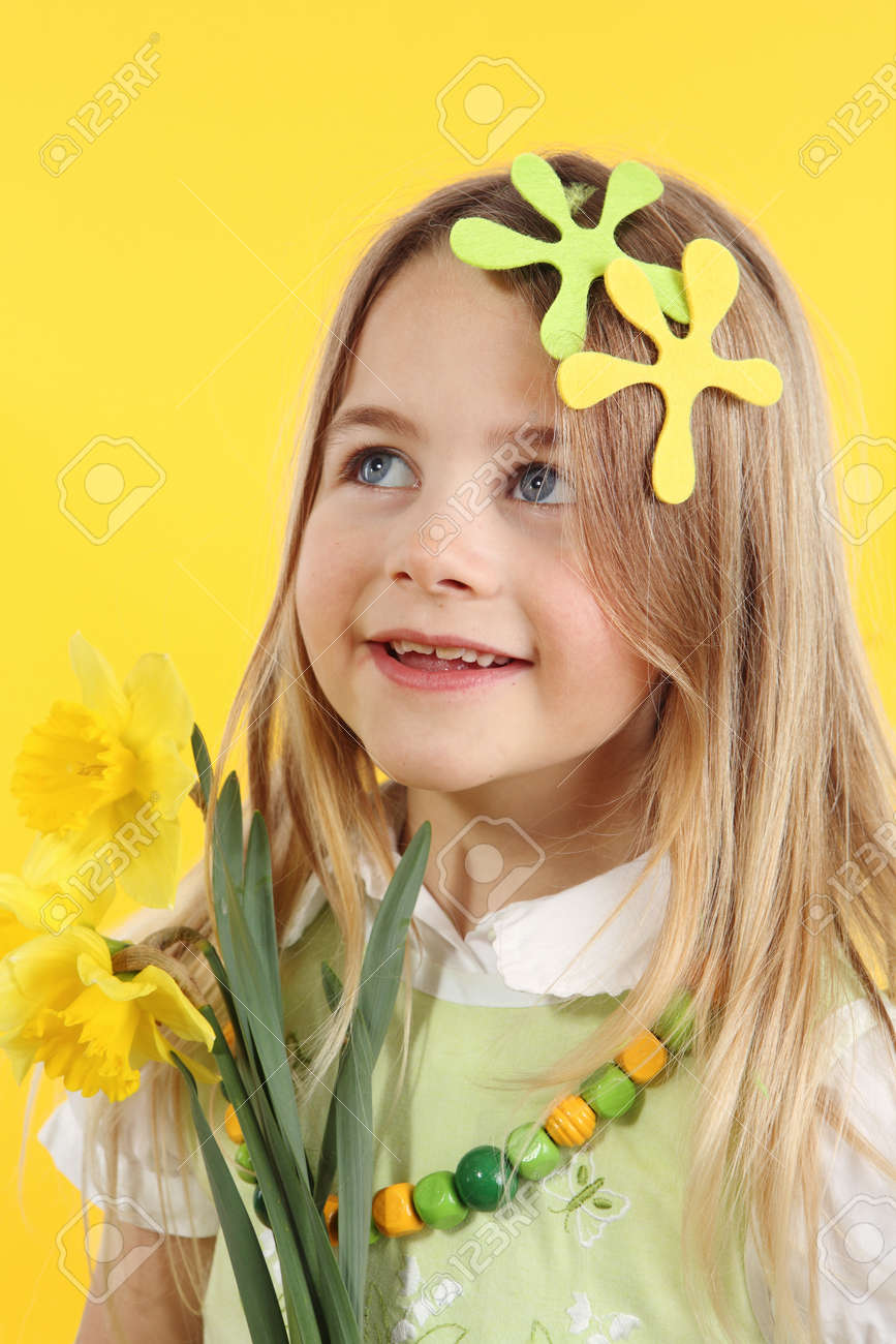 spring season concept: cute little girl with daffodil flowers for spring festival on yellow background. The child looks up to the side - 166404002 spring season concept: cute little girl with daffodil flowers for spring festival on yellow background. The child looks up to the side - 166404002