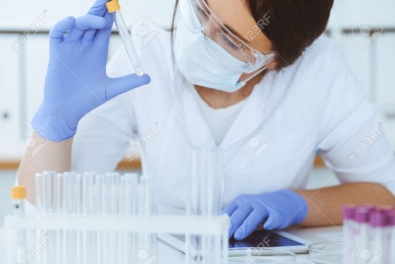 Close-up of professional female scientist in protective eyeglasses making experiment with reagents or blood test in laboratory. Medicine, biotechnology and research concept. - 138528428 Close-up of professional female scientist in protective eyeglasses making experiment with reagents or blood test in laboratory. Medicine, biotechnology and research concept. - 138528428