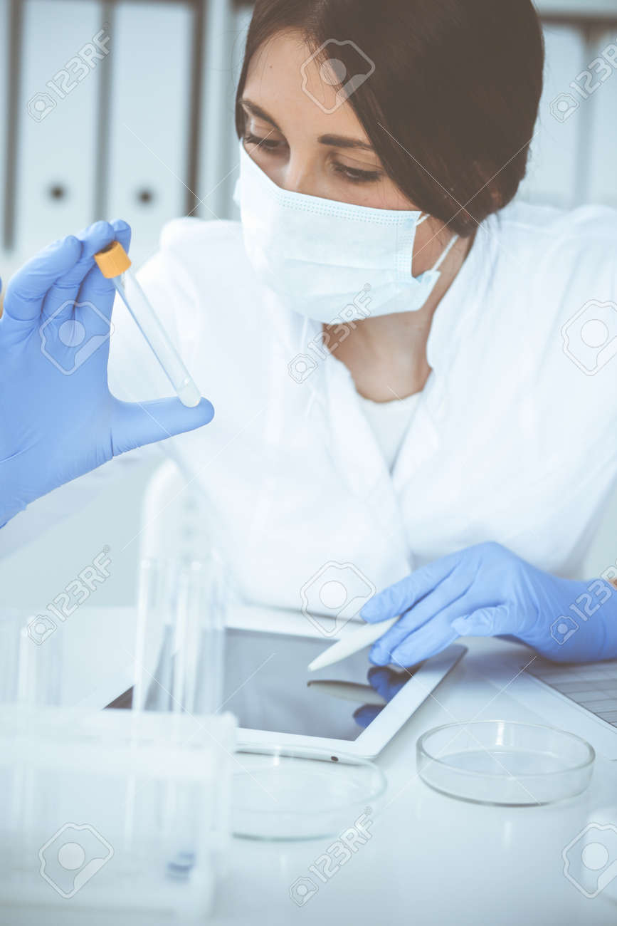 Close-up of professional female scientist in protective eyeglasses making experiment with reagents or blood test in laboratory. Medicine, biotechnology and research concept. - 140189958 Close-up of professional female scientist in protective eyeglasses making experiment with reagents or blood test in laboratory. Medicine, biotechnology and research concept. - 140189958