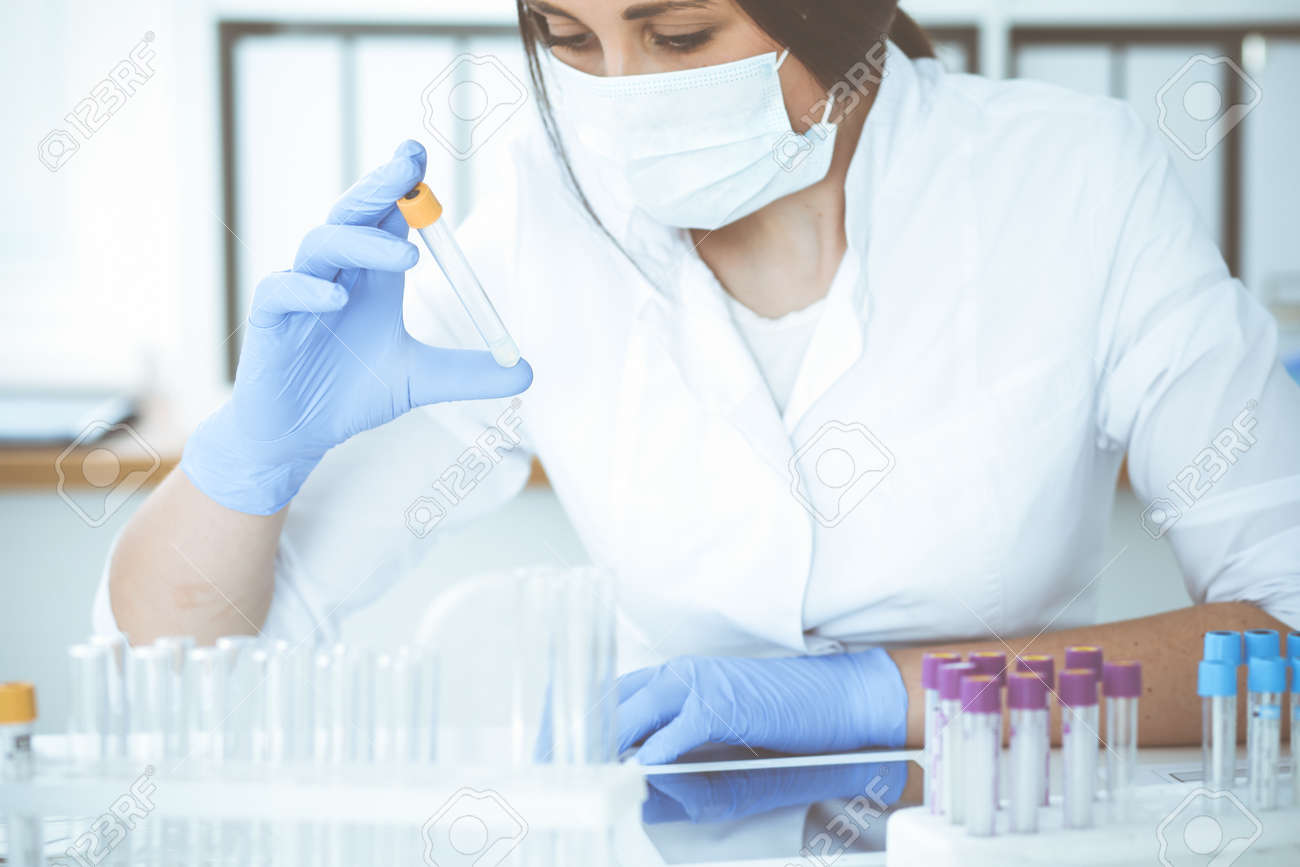 Close-up of professional female scientist in protective eyeglasses making experiment with reagents or blood test in laboratory. Medicine, biotechnology and research concept. - 140707771 Close-up of professional female scientist in protective eyeglasses making experiment with reagents or blood test in laboratory. Medicine, biotechnology and research concept. - 140707771
