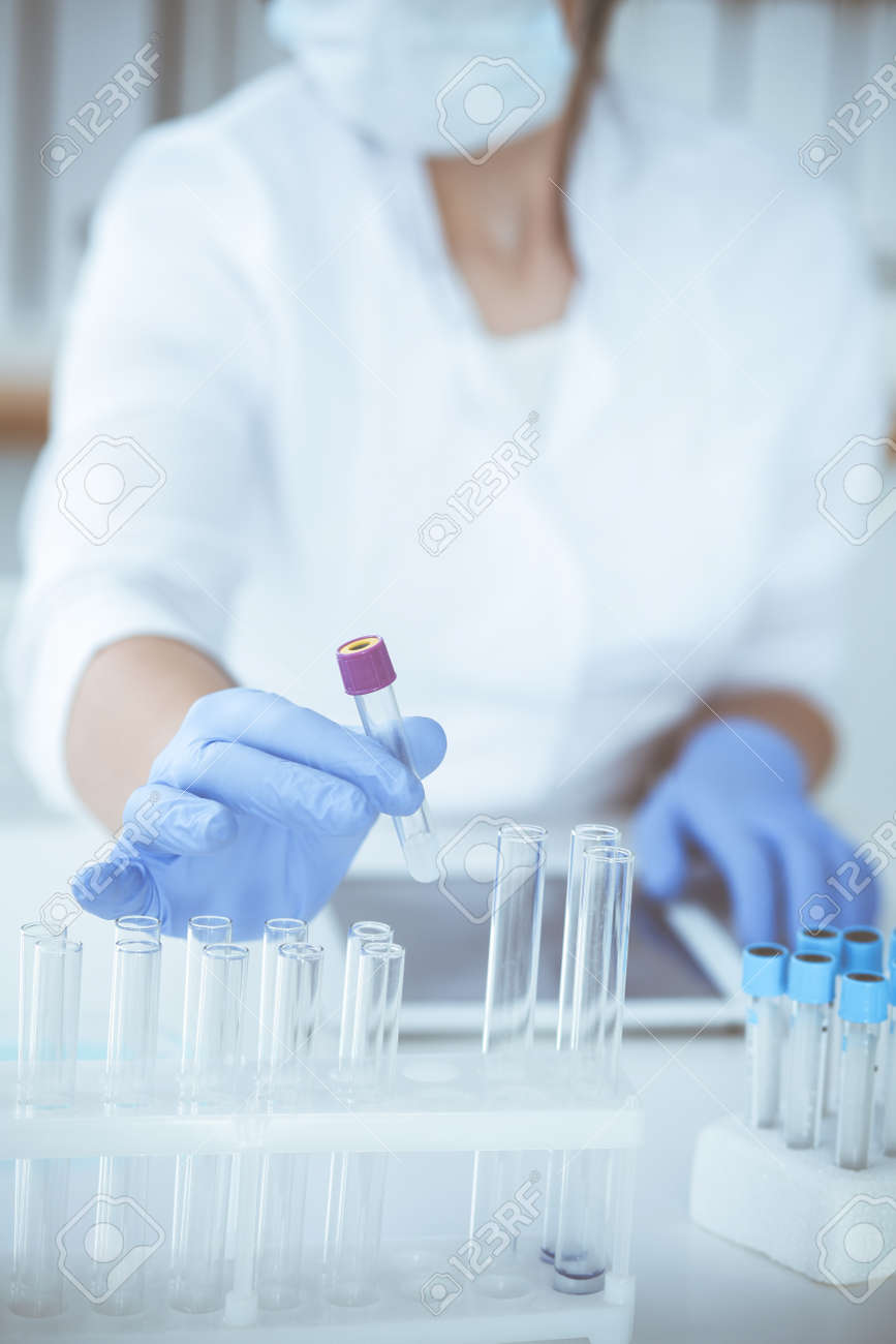 Close-up of professional female scientist in protective eyeglasses making experiment with reagents or blood test in laboratory. Medicine, biotechnology and research concept. - 140707828 Close-up of professional female scientist in protective eyeglasses making experiment with reagents or blood test in laboratory. Medicine, biotechnology and research concept. - 140707828