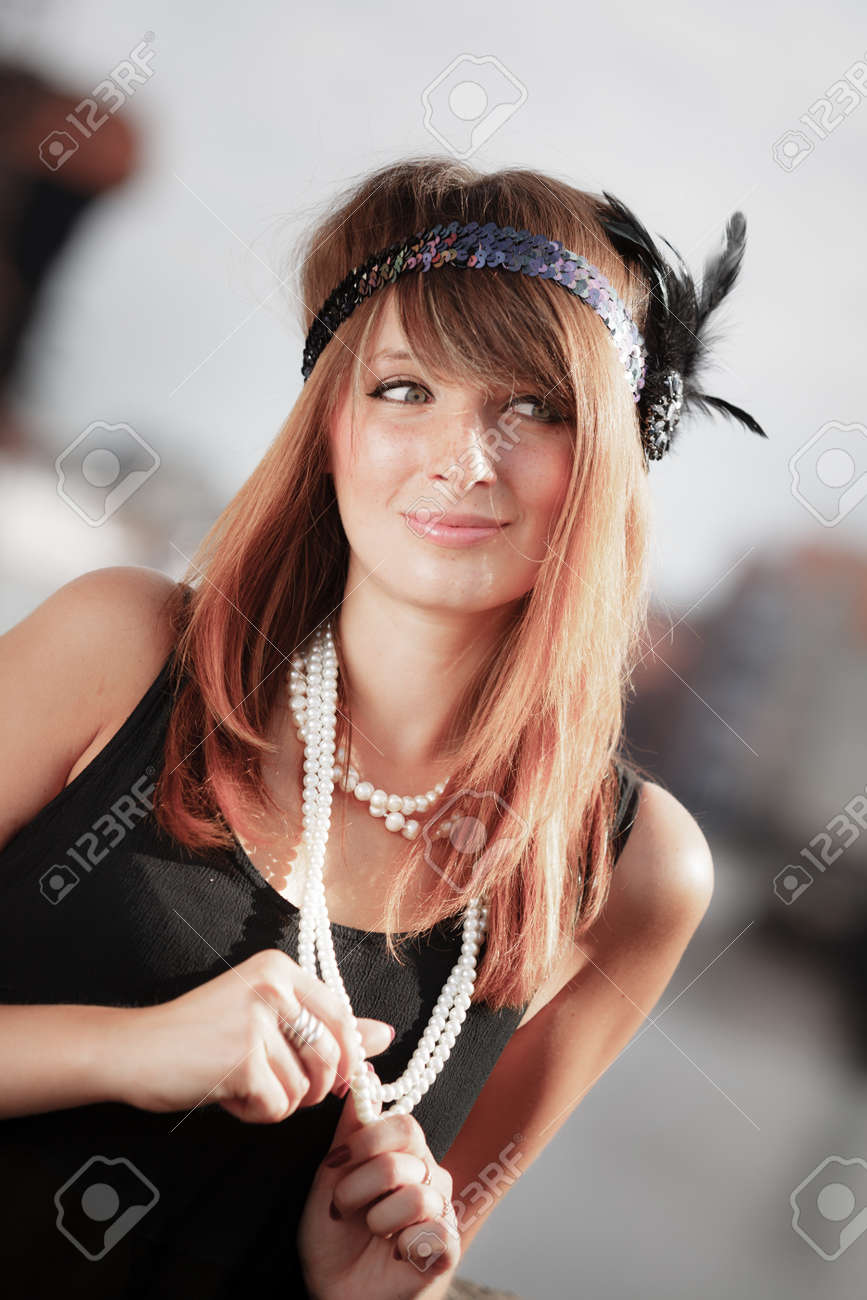 Rétro style de la mode femme vintage des années 1920 en rugissant bandeau avec collier de perles, en plein air. Ville fond