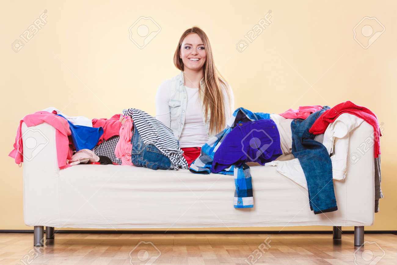 幸せな女は 乱雑なリビング ルームのソファー ソファに座って 若い女の子に囲まれて服の多くのスタック 無秩序と混乱の自宅 の写真素材 画像素材 Image 48844042