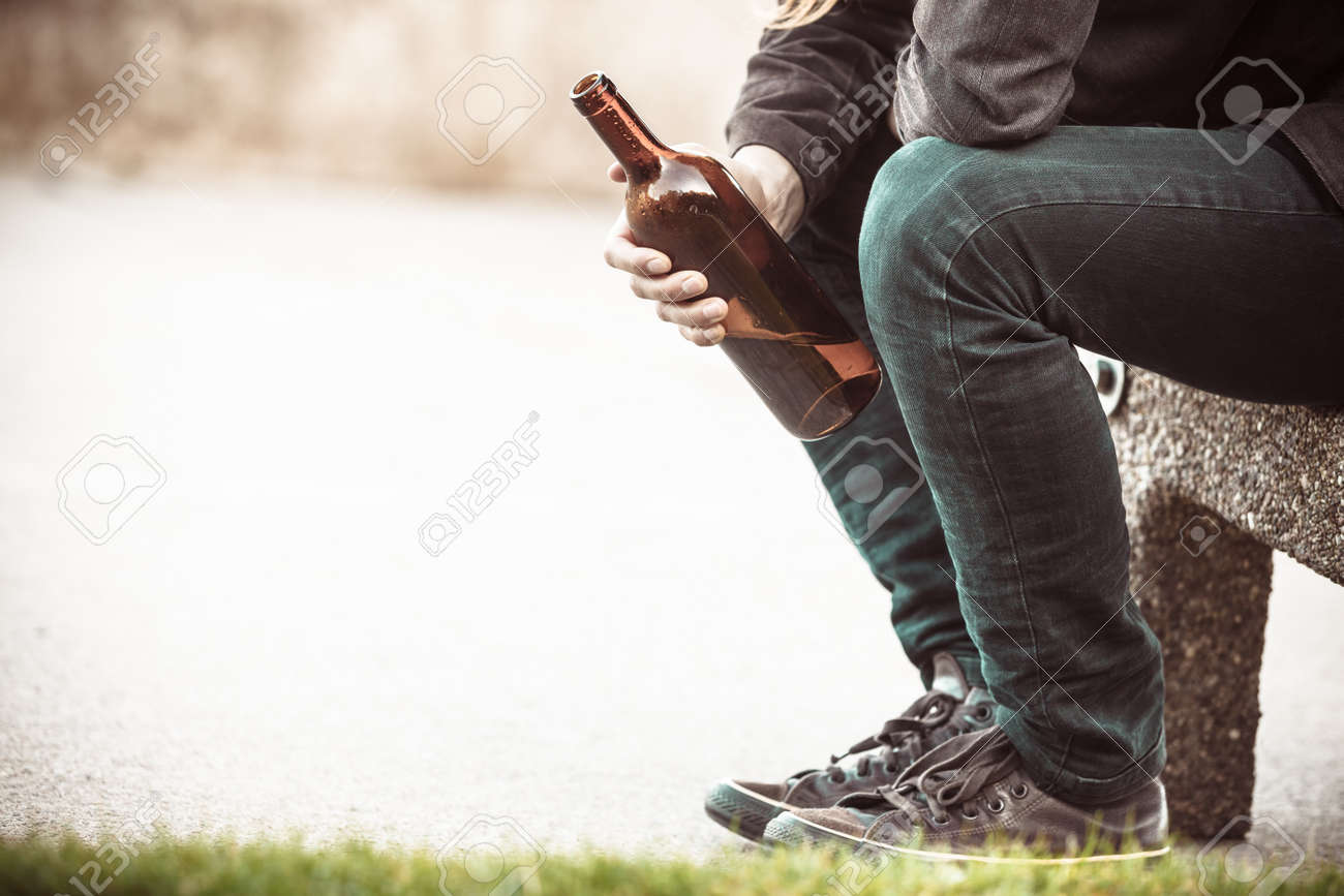 Man depressed with wine bottle sitting on bench outdoor. People abuse and alcoholism problems. - 54202969 Man depressed with wine bottle sitting on bench outdoor. People abuse and alcoholism problems. - 54202969