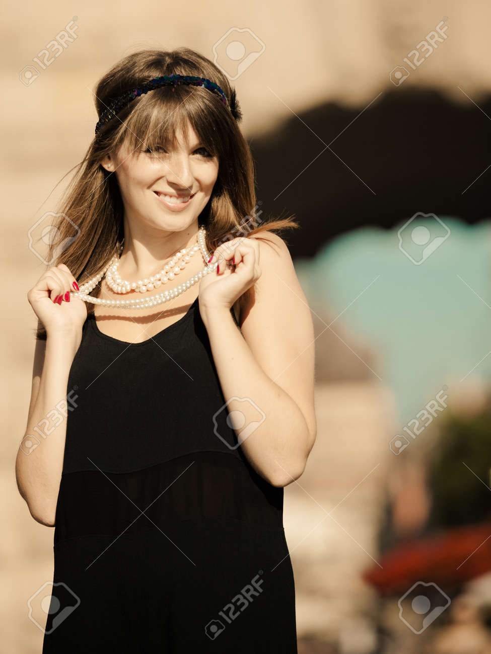 Rétro style de la mode femme vintage des années 1920 en rugissant bandeau avec collier de perles, en plein air. Ville arrière,plan. ton âge