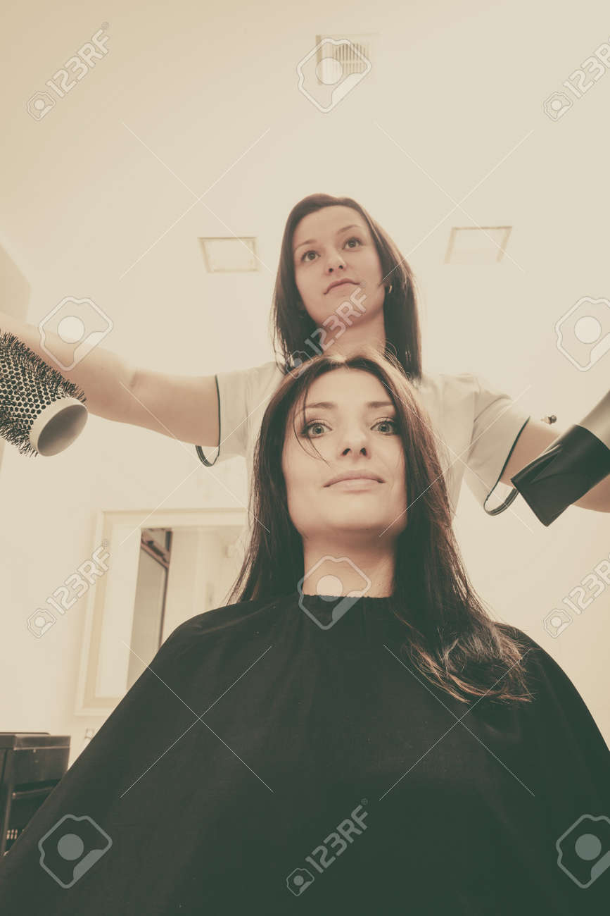 Friseur dunkel weibliche Haar mit professioneller Haartrockner Trocknen Wärmemodellierung Standard Bild